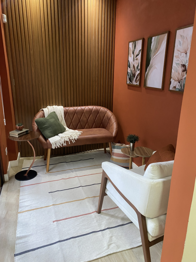 Sala de atendimento presencial do In Lumina, com sofá e poltrona confortáveis, tons terrosos e elementos naturais
